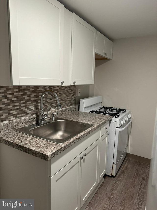 kitchen with white cabinets, dark wood-type flooring, sink, backsplash, and white gas stove