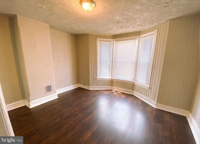 spare room with dark wood-type flooring and a textured ceiling