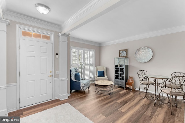 entrance foyer with ornate columns, ornamental molding, and hardwood / wood-style flooring