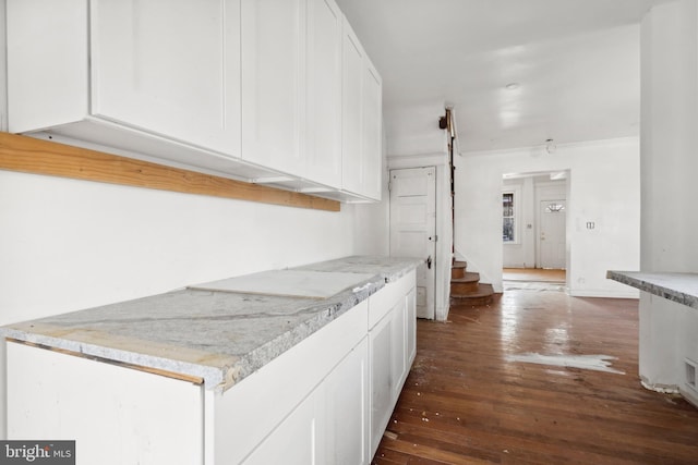 kitchen with white cabinetry, dark wood-type flooring, and light stone counters