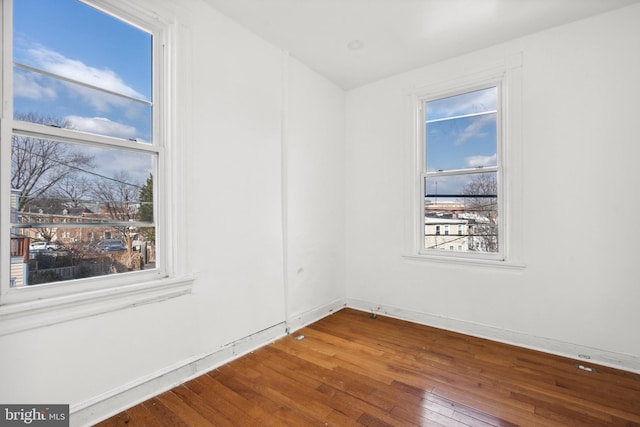 spare room with wood-type flooring and a healthy amount of sunlight