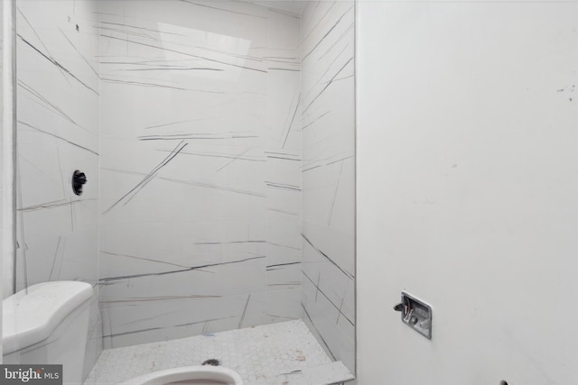 bathroom featuring a tile shower and toilet