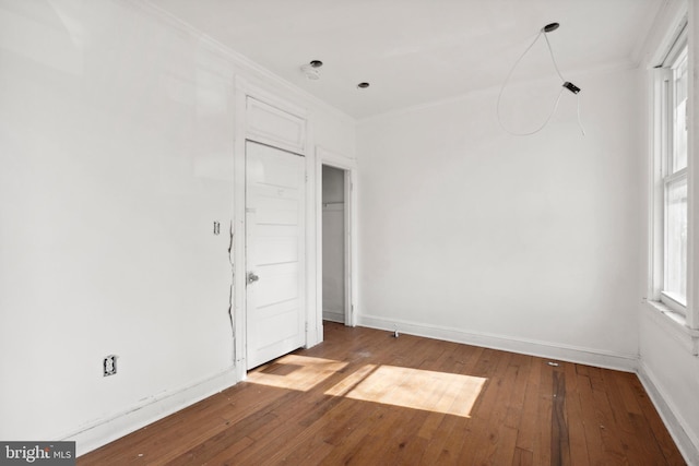 spare room featuring ornamental molding, a wealth of natural light, and hardwood / wood-style floors