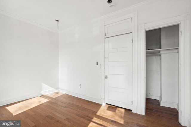 unfurnished bedroom with crown molding, dark wood-type flooring, and a closet