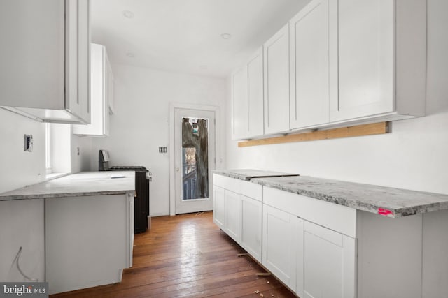 kitchen with white cabinetry, dark hardwood / wood-style flooring, range with gas stovetop, and light stone countertops