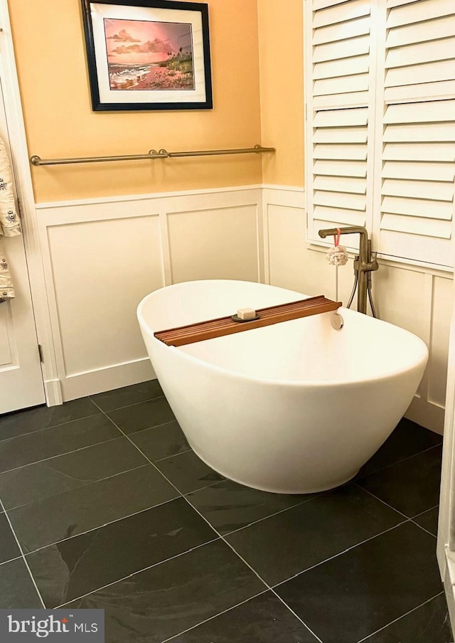 bathroom featuring a freestanding tub, a decorative wall, and a wainscoted wall