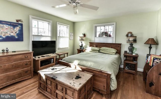 bedroom featuring ceiling fan, multiple windows, and light wood-type flooring