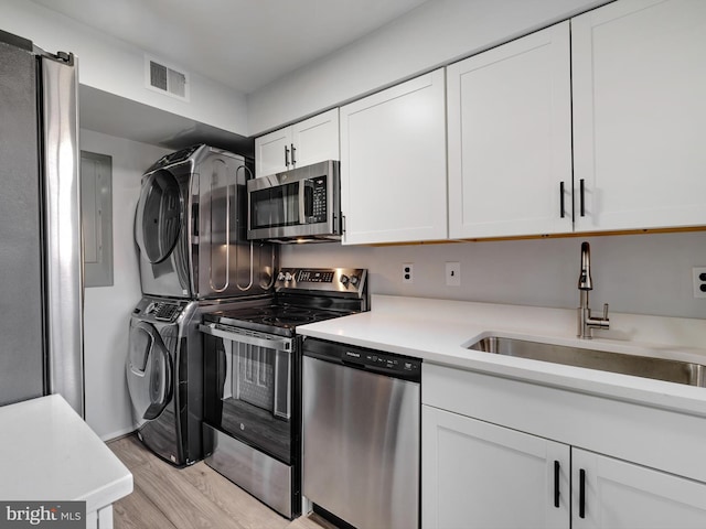 kitchen featuring stacked washer and dryer, a sink, visible vents, light countertops, and appliances with stainless steel finishes