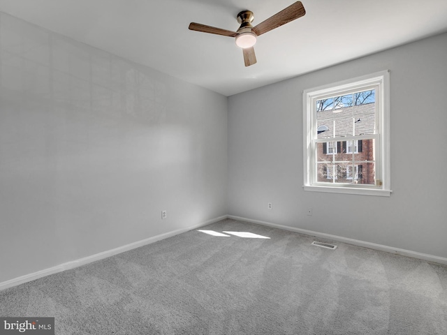 carpeted empty room with baseboards, visible vents, and ceiling fan