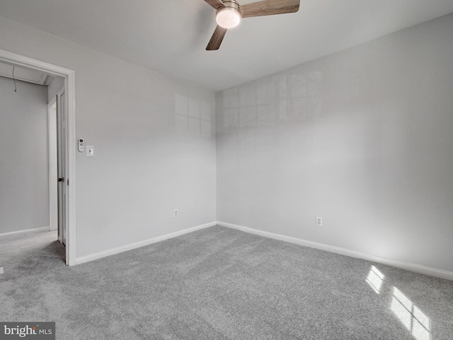 empty room featuring carpet floors, attic access, baseboards, and ceiling fan