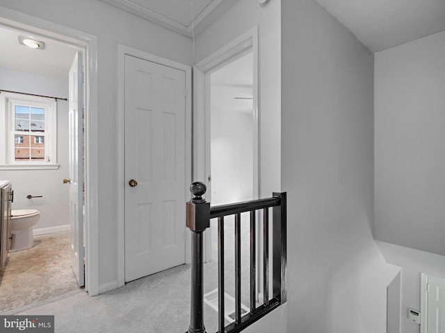 corridor with carpet, attic access, and baseboards