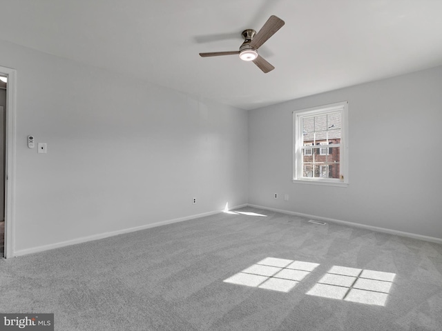 empty room with carpet floors, visible vents, baseboards, and a ceiling fan