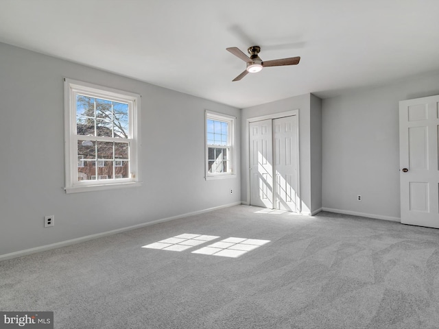 carpeted spare room featuring a ceiling fan and baseboards