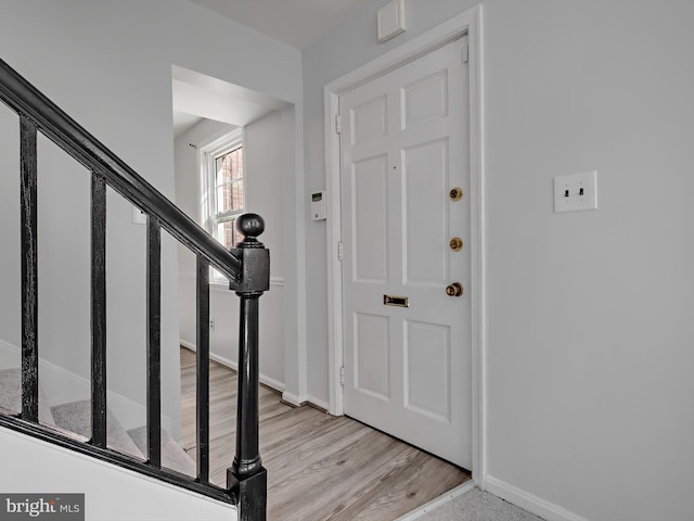 foyer entrance with light wood-style flooring, baseboards, and stairs