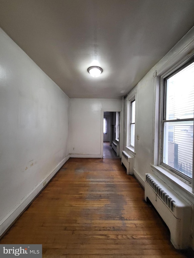 empty room featuring radiator, a baseboard heating unit, and dark hardwood / wood-style floors