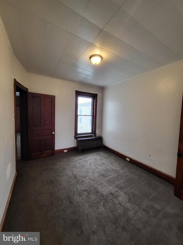 spare room featuring dark colored carpet