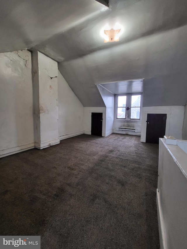 additional living space with baseboard heating, dark carpet, and vaulted ceiling