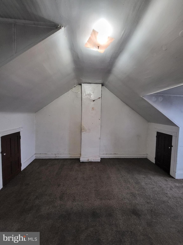 additional living space featuring vaulted ceiling and dark carpet