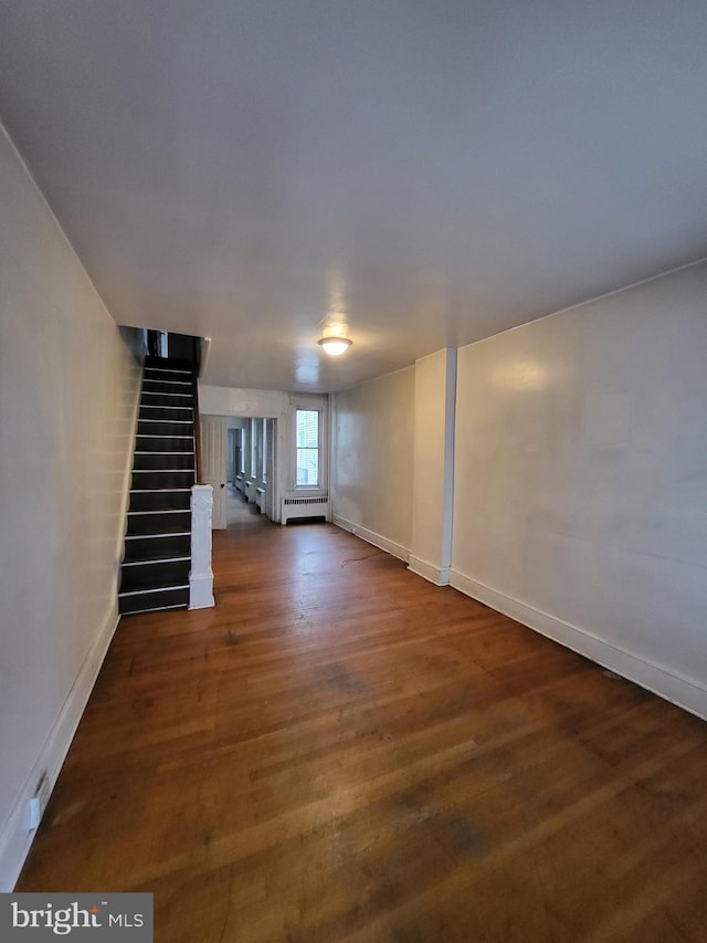 basement with dark wood-type flooring and a baseboard radiator