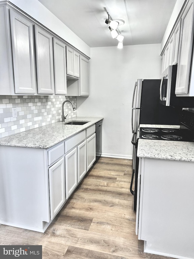 kitchen featuring gray cabinets, light hardwood / wood-style floors, decorative backsplash, sink, and stainless steel appliances