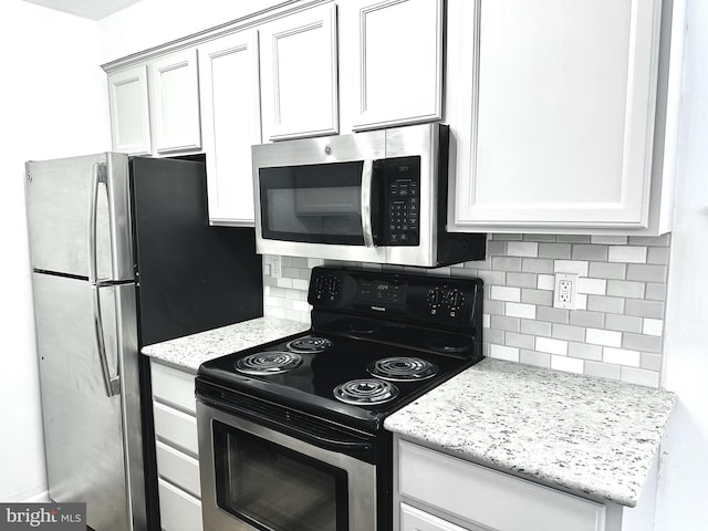 kitchen with white cabinets, decorative backsplash, light stone countertops, and stainless steel appliances