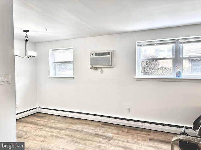 empty room featuring a baseboard heating unit, an inviting chandelier, a wall mounted AC, and hardwood / wood-style floors