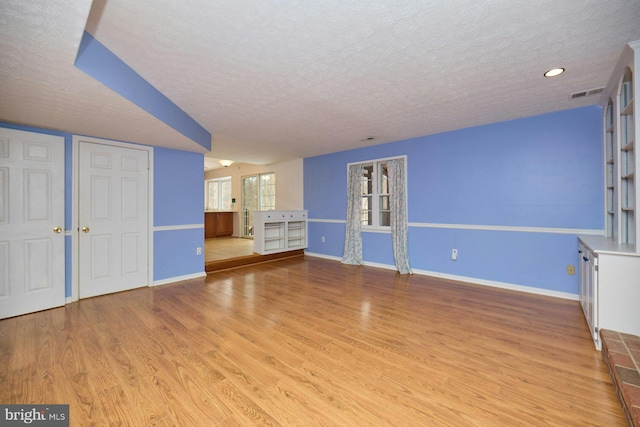 unfurnished living room featuring a textured ceiling and light hardwood / wood-style flooring