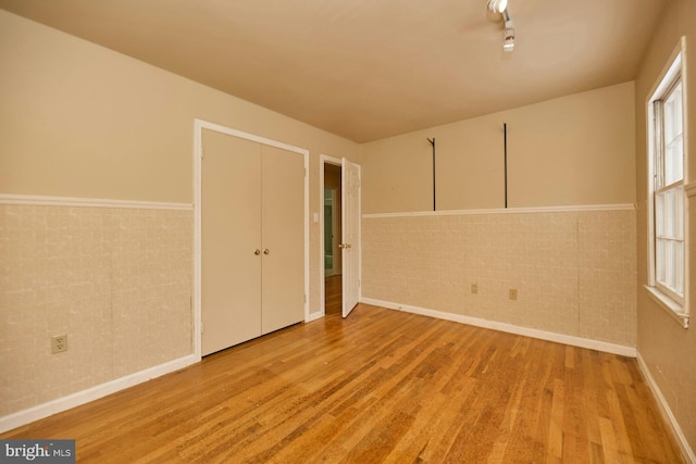 unfurnished bedroom with light wood-type flooring and brick wall