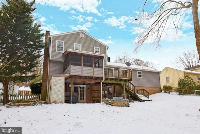 snow covered rear of property with a sunroom