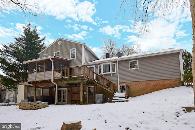 snow covered house featuring central AC unit, a sunroom, and a deck