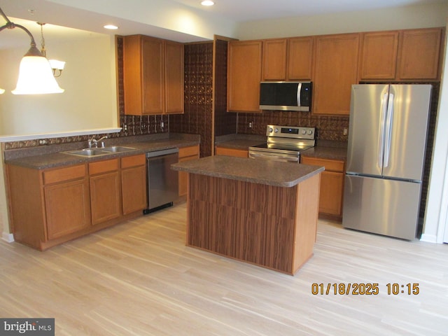 kitchen featuring pendant lighting, appliances with stainless steel finishes, a kitchen island, light hardwood / wood-style floors, and sink