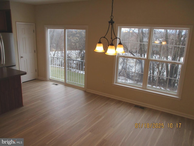 unfurnished dining area with a chandelier and wood-type flooring