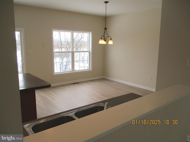 unfurnished dining area featuring a notable chandelier and hardwood / wood-style floors