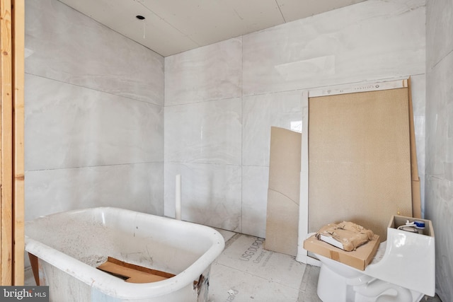 bathroom featuring tile walls and a tub to relax in