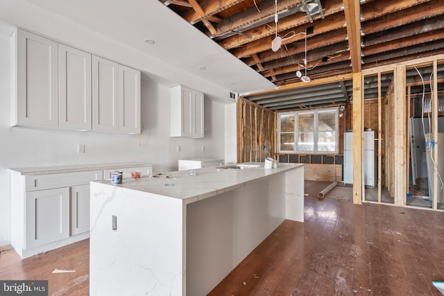 kitchen with white cabinetry, light stone counters, a center island, white refrigerator, and hardwood / wood-style floors