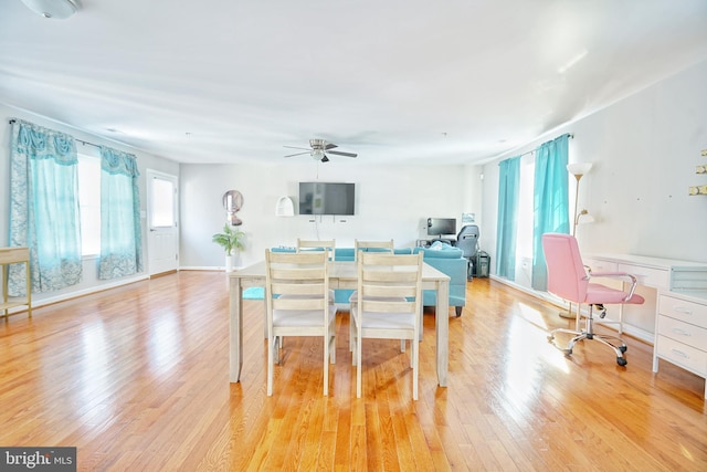 dining area with built in desk, light wood-type flooring, and ceiling fan