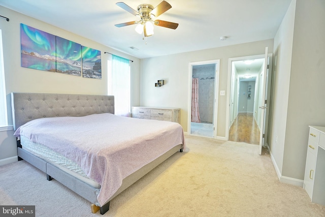 bedroom featuring ceiling fan, light colored carpet, and ensuite bath