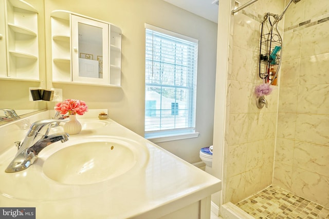 bathroom featuring toilet, tiled shower, and vanity