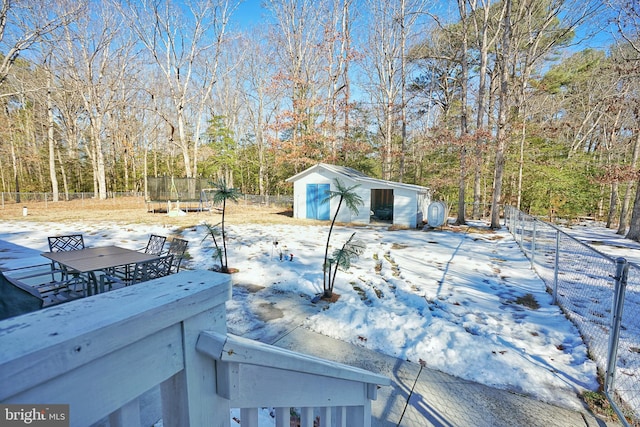 snowy yard with an outbuilding, a trampoline, and a garage