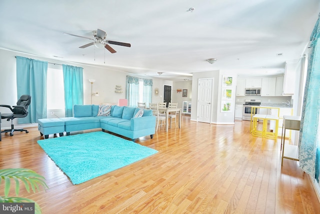 living room featuring ceiling fan, a wealth of natural light, light hardwood / wood-style flooring, and sink