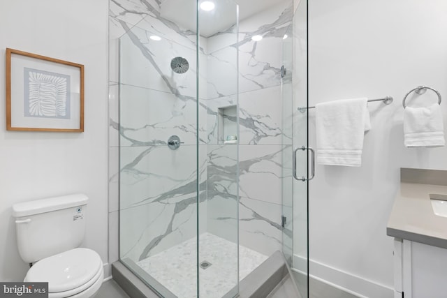 bathroom featuring toilet, a shower with shower door, and vanity