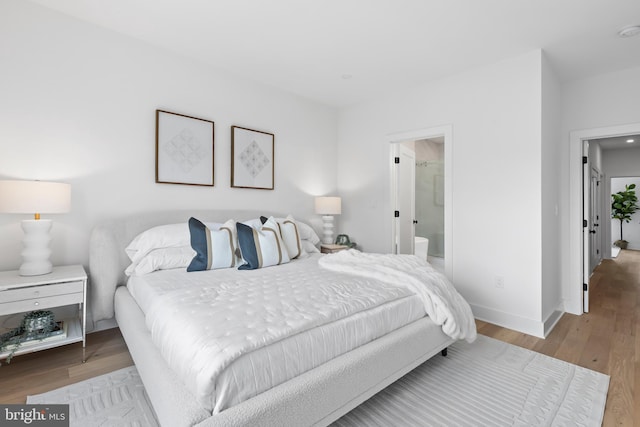 bedroom featuring ensuite bathroom and hardwood / wood-style flooring