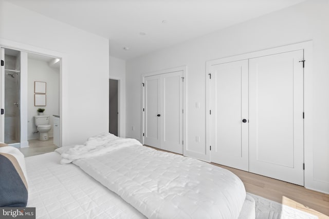 bedroom with multiple closets, ensuite bathroom, and light hardwood / wood-style floors