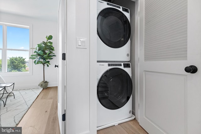 laundry room with light hardwood / wood-style floors and stacked washer / dryer