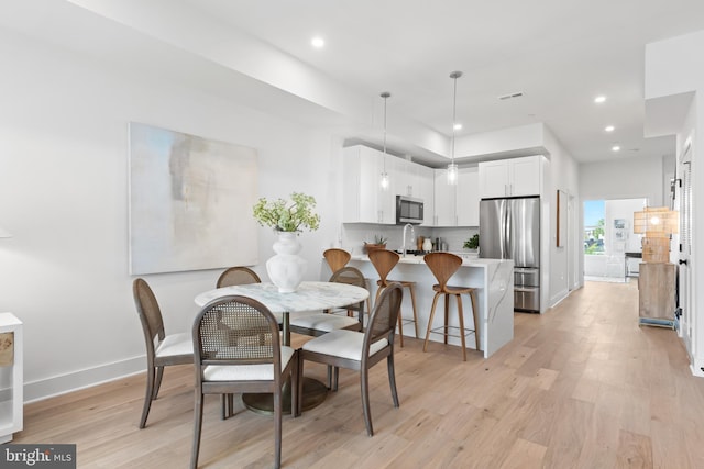 dining space with light wood-type flooring and sink