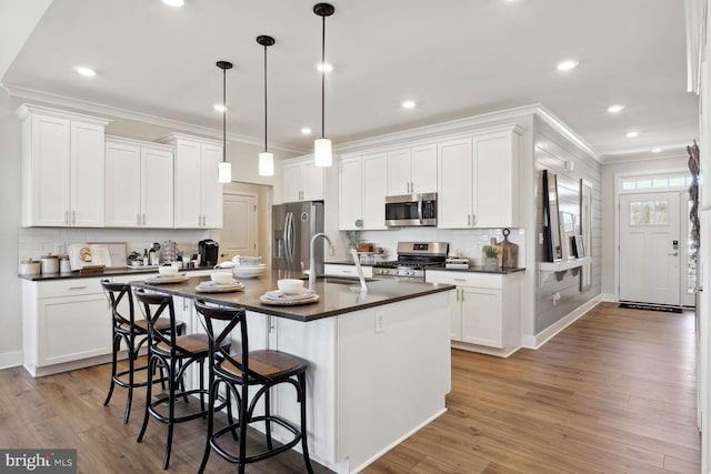 kitchen featuring appliances with stainless steel finishes, white cabinetry, and a kitchen island with sink