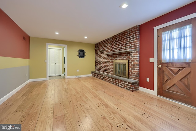 unfurnished living room with a fireplace and light wood-type flooring