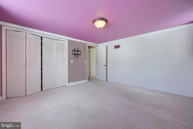 unfurnished bedroom featuring ornamental molding, light carpet, and a closet