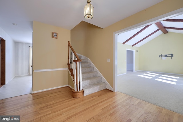 stairway with wood-type flooring and vaulted ceiling with skylight