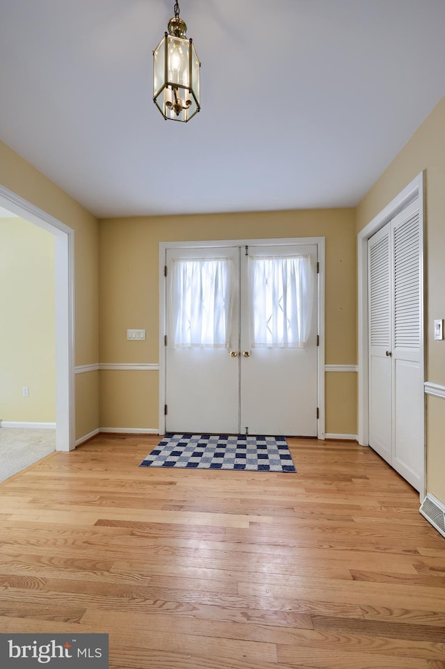 entrance foyer featuring a notable chandelier, light hardwood / wood-style floors, and french doors